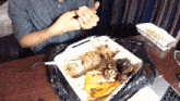 a man is sitting at a table with a container of food on it