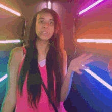a woman in a pink tank top is standing in front of a colorful background