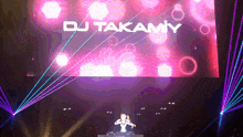 dj takamiy performs on a stage with a large screen behind him
