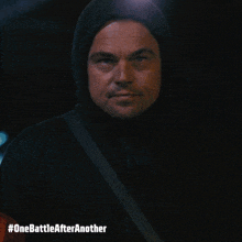 a man wearing a hooded jacket with the hashtag #onebattleafteranother on the bottom