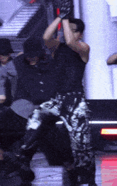 a man wearing a black tank top and silver pants is dancing on a stage