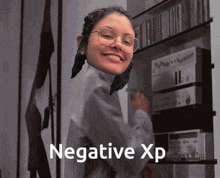 a woman wearing glasses stands in front of a shelf that says " negative xp " on it