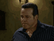 a man in a striped shirt is standing in a room