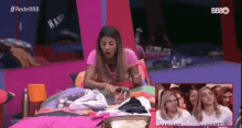 a woman in a pink shirt is sitting on a bed in a bedroom .