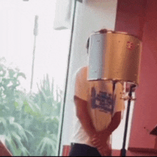 a person standing in front of a window with a bucket on their head that says ' a ' on it
