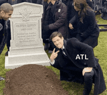 a man kneeling in front of a grave that says oliver queen 1985-2019