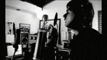 a black and white photo of a man singing into a microphone with a sign that says ' x ' on it