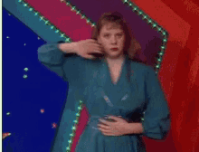 a woman in a blue dress is holding her stomach in front of a red and blue background .