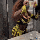 a woman in a caution tape costume is dancing in front of a mirror .