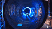 a man is walking through a blue tunnel with the letters a & e on the bottom