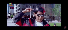 a man wearing a hat and sunglasses is standing on a city street