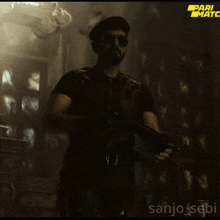 a man holding a gun in a dark room with the words pari match on the bottom right