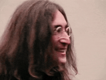a man with long hair and glasses is making a funny face .