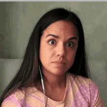 a woman wearing headphones makes a funny face while looking at the camera