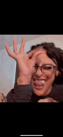 a woman with glasses and a small heart tattoo on her wrist .