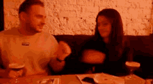 a man and a woman are sitting at a table in a restaurant with drinks .