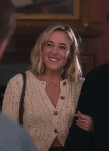 a woman wearing a white sweater with buttons on it smiles