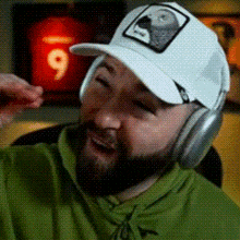 a man with a beard wearing a white hat and headphones is laughing .