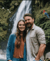 a man and woman standing in front of a waterfall