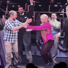 a woman in a pink shirt is dancing with a group of people
