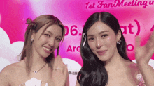 two women standing in front of a sign that says " 1st fan meeting "