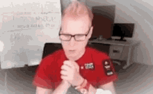 a man wearing glasses and a red shirt is sitting in front of a white board that says " i radiomagic "