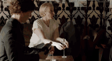 a man is pouring a glass of wine into a woman 's glass while they sit at a table