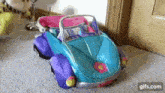 a blue and purple toy car is sitting on the floor in a room .
