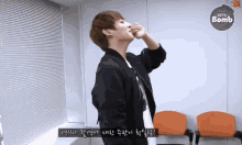 a man in a black jacket is standing in a room with a sign that says ' bts bomb ' on it .