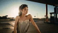 a woman in a dress is standing in a parking lot at sunset .