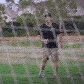 a man in a black shirt is standing in a grassy field