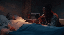 a man prays in front of a woman in a hospital bed