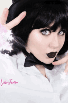 a woman with black hair and a bow tie is wearing a white shirt and black lipstick .