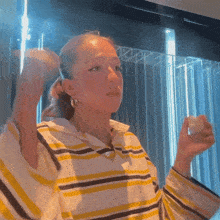 a woman in a yellow and white striped shirt is holding something in her hand
