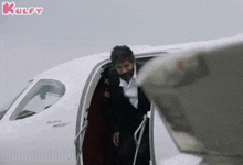 a man in a suit and tie is getting out of a private jet .