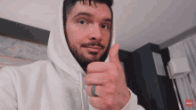 a man in a white hoodie gives a thumbs up