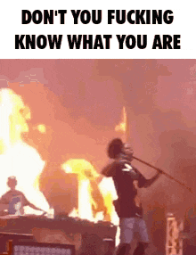 a man is playing a trumpet on a stage in front of a flaming wall .