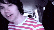 a man in a striped shirt is sitting in a car .