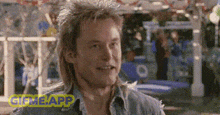 a man with a mullet and a denim shirt is smiling in a pixelated image .