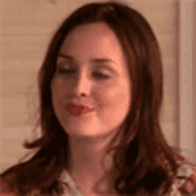 a close up of a woman 's face with her eyes closed and red lipstick on her lips .