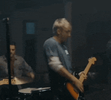 a man singing into a microphone while another man plays guitar