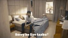 a man is sitting on a bed with the words sorry ke liye tazku written below him