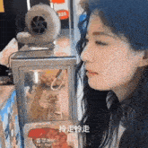 a woman is standing in front of a display case with chinese writing on it