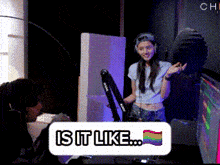 a woman wearing headphones stands in front of a microphone with a rainbow flag and the words is it like on it