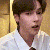 a young man in a white shirt and tie is looking at the camera .