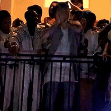 a crowd of people standing behind a fence including a man with sunglasses on his head