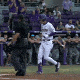 a baseball player wearing a louisiana tigers uniform is walking towards the dugout