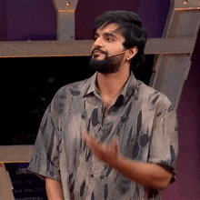 a man with a beard is wearing a dirty shirt and has his hand out