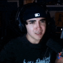 a man wearing headphones and a hat with the letter b on it is making a funny face