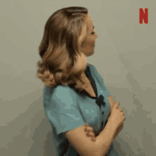 a woman in a blue dress is standing with her arms crossed .